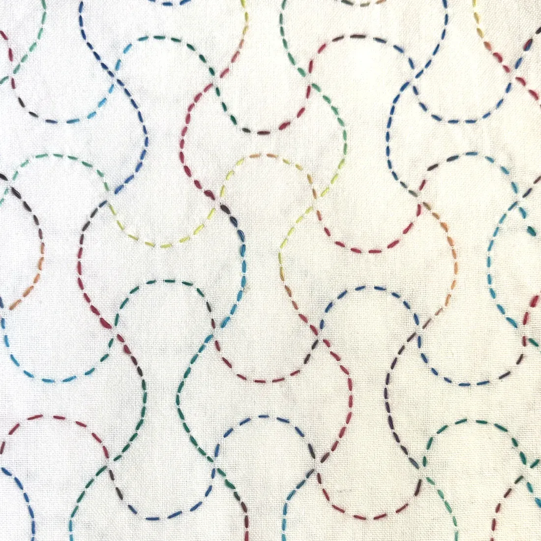 Nagare Manji (flowing current) sashiko pattern hand-stitched in rainbow thread on natural linen